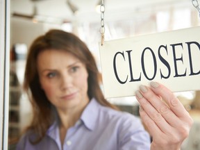 A store owner turns a closed sign in a shop doorway in this stock photo. (Getty Images)