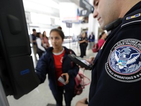 U.S. Customs and Border Protection officer Julio Corro, right, helps a passenger navigate one of the new facial recognition kiosks at a United Airlines gate before boarding a flight to Tokyo, Wednesday, July 12, 2017, at George Bush Intercontinental Airport, in Houston. The Trump administration intends to require that American citizens boarding international flights submit to face scans, something Congress has not explicitly approved and privacy advocates consider an ill-advised step toward a surveillance state. (AP Photo/David J. Phillip)