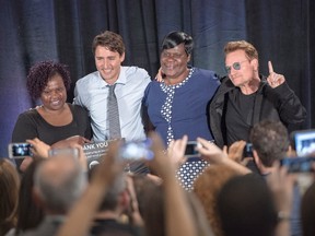 Prime Minister Justin Trudeau, rock band U2's Bono, right, and AIDS activists Patricia Aserrio Ochieng and Consolata Opiyo, left, pose for photos after a town hall meeting for the One Campaign for the fight against poverty, in Montreal on Saturday, September 17, 2016. THE CANADIAN PRESS/Ryan Remiorz
