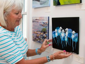 Taylor Bertelink/The Intelligencer
Susan Walker adjusts one of her paintings she painted for the One by One Show that kicked off Thursday night at 4 p.m. at the Belleville Art Association Gallery.