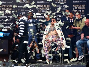 Floyd Mayweather Jr. looks on as money rains down on Conor McGregor during World Press Tour event at Barclays Center on July 13, 2017. (Mike Stobe/Getty Images)