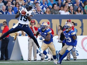 Argonauts' S.J. Green snags the pass in front of WBlue Bombers' Brian Walker (22) and TJ Heath (23) in Winnipeg on Thursday. (John Woods/The Canadian Press)