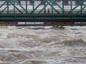 A pedestrian walks across the Chaudiere bridge as high waters on the Ottawa river pass just underneath in May. Adrian Wyld/CP