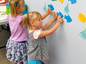 Sticking their Atlantic symbol on the wall on the fourth floor of the West Perth public library, based on the number of books they read, are sisters Wendy and Nicole Tschudi (right), last Friday, July 14. ANDY BADER/MITCHELL ADVOCATE