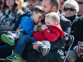 Brad Aschenbrenner, husband of RCMP officer Sarah Beckett, holds his sons Lucas (left) and Emmit during the Canadian Police and Peace Officers' Memorial Service on Parliament Hill on Sunday, Sept. 25, 2016. THE CANADIAN PRESS/Justin Tang