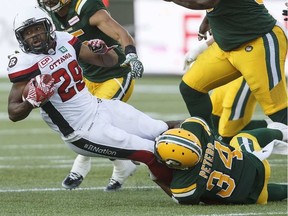 Redblacks tailback William Powell (29) is tackled by Eskimos defender Garry Peters (34) during first-half action in Edmonton on Friday night. THE CANADIAN PRESS/Jason Franson