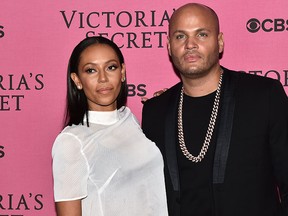 Melanie Brown and her husband Stephen Belafonte pose for pictures on the pink carpet with an unidentified guest upon arrival for the 2014 Victoria's Secret Fashion Show at Earl's Court exhibition centre in London on Dec. 2, 2014. (LEON NEAL/AFP/Getty Images)