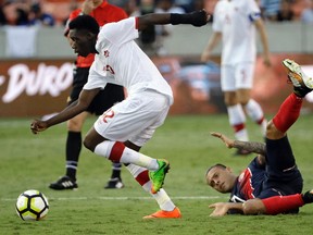 Costa Rica's David Ramirez, right, hits the ground after being tackled by Canada's Alphonso Davies, left, in the second half of a CONCACAF Gold Cup soccer match in Houston, Tuesday, July 11, 2017.