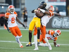 B.C. Lions defensive back Loucheiz Purifoy holds on to Hamilton Tiger-Cats’ Jalen Saunders after Saunders’ 60-yard reception during the first half of yesterday’s game in Hamilton. The Canadian Press