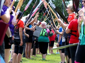 Marilyn Foster of Norwood walks under an arch of paddles following a breast cancer survivor's race at the Trenton Dragon Boat Festival on  Saturday July 15, 2017 in Trenton, Ont. Tim Miller/Belleville Intelligencer/Postmedia Network