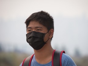 A young man wears a mask because of smoke in the air from wildfires burning in central B.C., while rushing to catch a bus in Kamloops, B.C., on Monday July 10, 2017. More than 200 wildfires are burning in the province and an estimated 14,000 people have been evacuated from their homes. (THE CANADIAN PRESS/Darryl Dyck)