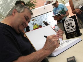 Phil Egan signs a copy of his book Walking Through Fire, a history of Sarnia's fire service, at an event Saturday in Sarnia. The historian was honoured by firefighters for his work. Tyler Kula/Sarnia Observer/Postmedia Netwo