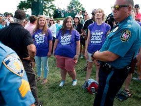 Protesters watch as US President Donald Trump arrives at the 72nd US Women's Open Golf Championship at Trump National Golf Course in Bedminster, New Jersey, July 16, 2017. SAUL LOEB/AFP/Getty Images