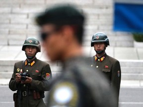 In this April 17, 2017, file photo, two North Korean soldiers look at the south side as a South Korean soldier, center, stands guard while U.S. Vice President Mike Pence visited the border village of Panmunjom which has separated the two Koreas since the Korean War. (AP Photo/Lee Jin-man, File)