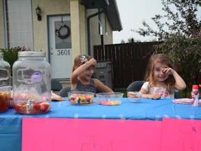 Kaylee Simard (left) and Ellie-Anna Fuoco sell lemonade, candy and popsicles for charity at their stand on 55 Ave. on June 10 (Peter Shokeir | Whitecourt Star).