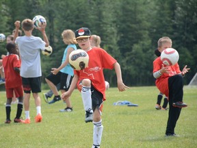 Campers practice kneeing soccer balls during Athletes in Action Soccer Camp at Rotary Park on July 12 (Peter Shokeir | Whitecourt Star).