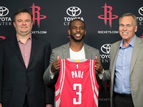 Chris Paul (centre) holds his new jersey as he is joined by Rockets GM Daryl Morey (left) and coach Mike D'Antoni (right) during a news conference in Houston on Friday, July 14, 2017. (David J. Phillip/AP Photo)