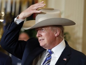 U.S. President Donald Trump tries on a Stetson hat during a "Made in America," product showcase featuring items created in each of the U.S. 50 states, Monday, July 17, 2017, at the White House in Washington. Stetson is base in Garland, Texas. (AP Photo/Alex Brandon)