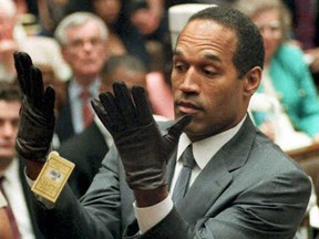 This June 21, 1995 file photo shows former American football star and actor O.J. Simpson looking at a new pair of extra-large gloves that prosecutors had him put on during his double-murder trial in Los Angeles. (AFP/PHOTO)