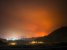 A wildfire burns on a mountain in the distance east of Cache Creek behind a house in Boston Flats, B.C., in the early morning hours of Monday July 10, 2017. (THE CANADIAN PRESS/Darryl Dyck)