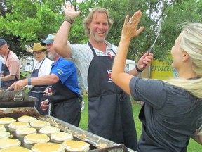 Rotarians Mark Lumley and Melissa Halloran high five in this file photo while cooking pancakes during the Rotary Club of Sarnia Mackinac race breakfast last year at Point Edward's Waterfront park. This year's breakfast is Saturday, 7 a.m. to 11 a.m. (File photo)