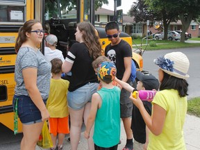 ebecca Johnson, left, and Krisziel Rances, in black shirt, are spending their summer employed through the Focus on Youth program gaining work experience as well as a co-op credit. They're helping Numeracy and Literacy Camp participants board a bus for a field trip Thursday afternoon. (Julia McKay/The Whig-Standard)