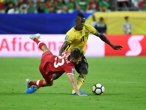 Michael Petrasso of Canada is knocked to the turf while battling for a loose ball with Cory Burke of Jamaica during the CONCACAF Gold Cup at University of Phoenix Stadium on July 20, 2017. (Photo by Norm Hall/Getty Images)