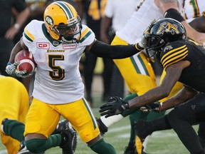 Edmonton Eskimos running back Travon Van (5) gives a straight arm to Hamilton Tiger-Cats defensive back Will Hill (1) during first half CFL football action in Hamilton, Ont., on Thursday, July 20, 2017.