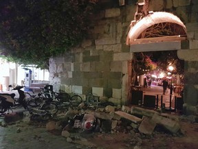 People walk near a damaged building after an strong earthquake on the Greek island of Kos early Friday, July 21, 2017. (Kalymnos-news.gr via AP)