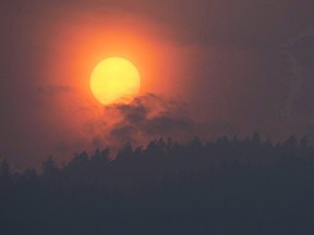 Smoke is seen rising in front of the sun as a wild fire burns near Little Fort, B.C., on July 11, 2017. Fifty experts from Australia are expected to arrive today to help with the wildfire battle in British Columbia's central and southern Interior. Fire information officer Navi Saini says they'll put the Australians where the need is greatest, taking advantage of their expertise in equipment, technology and logistical support. (THE CANADIAN PRESS/Jonathan Hayward)