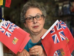 A sample red ensign flag is held by the Flag Shop owner Phyllis Bright in Edmonton, July 12, 2017. (Ed Kaiser/Postmedia)