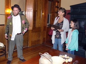 In this July 14, 2017 photo, actor Allan Smith, left, portraying the Mark Twain character Muff Potter, answers questions from 10-year-old Emma Connell, right, and her grandmother, Joan Rossitto, both of Arizona, during a "Clue" tour of the Mark Twain House in Hartford, Conn. The tour allows visitors to interact with Twain characters while playing a live-action version of the board game. (AP Photo/Pat Eaton-Robb)