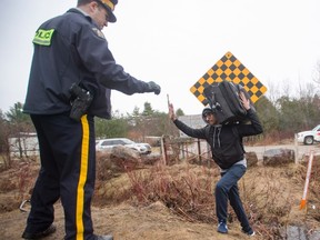 An RCMP officer warns a man to cross at the legal border crossing or he will be arrested at the border from New York into Canada on Wednesday, March 8, 2017 in Hemmingford, Quebec. THE CANADIAN PRESS/Ryan Remiorz