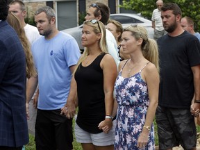 In this Wednesday, July 29, 2015, file photo, Carly Black, center, mother of Austin Stephanos, one of the missing teenage fishermen, listens as the U.S. Coast Guard makes a statement outside of the homes of the two teenagers missing since a fishing trip in Tequesta, Fla. (AP Photo/Lynne Sladky, File)