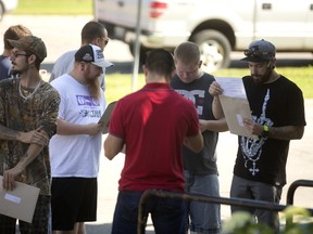 Workers at the closing Siemens wind-turbine blade plant in Tillsonburg emerge from their meeting to check their severance packages on Tuesday. (Mike Hensen/The London Free Press)