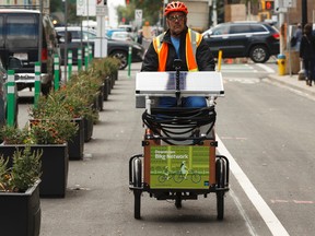 Peter Mueller, a Park Operations Coordinator with the City of Edmonton, demonstrates how one of two operating solar-power watering tricycles is used during a press conference on 103 Street in downtown Edmonton on Friday, July 21, 2017. Ian Kucerak / Postmedia