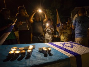 Israelis take pictures of candles in the Israeli settlement of Halamish, Saturday, July 22, 2017. (AP Photo/Tsafrir Abayov)