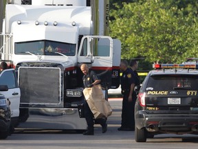 San Antonio police officers investigate the scene where eight people were found dead in a tractor-trailer loaded with at least 30 others outside a Walmart store in stifling summer heat in what police are calling a horrific human trafficking case in San Antonio, Texas, on Sunday, July 23, 2017. (Eric Gay/AP Photo)