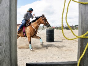 Ashley Bull is framed through the fence as she competes in the adult barrel category at the Mitchell Horse Club show at Moore Stables in Mitchell July 8.  ANDY BADER/MITCHELL ADVOCATE