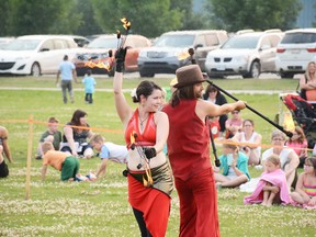 Performers Meghan Ferguson (left) and Joey Vedres pose with their flaming objects at Arts in the Park in Rotary Park on July 19 (Peter Shokeir | Whitecourt Star).
