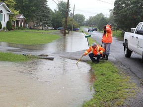 City workers try to unclog a culvert on Eunice Drive in Kingston on July 24 after more than 100 millimetres of rain fell on the city, flooding low-lying areas. (Elliot Ferguson/The Whig-Standard)