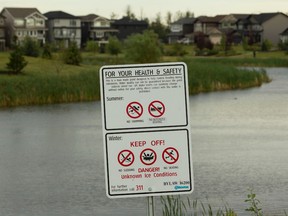 A warning sign next to a stormwater pond where Khrystyna Maksymova, 14, drowned is seen near 82 Street and Crystallina Nera Way in Edmonton on Monday, July 24, 2017. Ian Kucerak / Postmedia