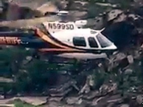In this Sunday, July 23, 2017, image taken from video provided by the Pima County Sheriff's office, a stranded hiker is rescued from torrential flash flood waters near Tucson, Ariz. Over a dozen hikers were stranded Sunday in a scenic canyon on the outskirts of Tucson, just over a week after a flash flood killed 10 members of an extended family more than 140 miles to the north. (Pima County Sheriff via AP)