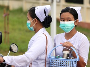 Nurses cover their faces with masks to protect from the spread of the swine flu outside the Naypyitaw hospital, Tuesday, July 25, 2017, in Naypyitaw, Myanmar. Public health officials in Myanmar say that H1N1 flu, also known as swine flu, has killed three people out of 13 confirmed cases of the infection. (AP Photo/Aung Shine Oo)