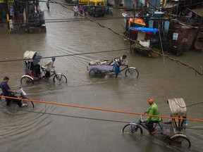 Indian rickshaw pullers wade through a water logged street following heavy rains in Allahabad, India, Tuesday, July 25, 2017. The monsoon season in India runs from June to September. (AP Photo/Rajesh Kumar Singh)