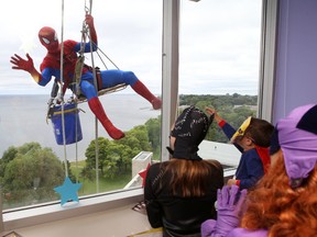 A window washer dressed as Spider-Man waves to patients and volunteers at Kingston General Hospital on Tuesday. (Elliot Ferguson/The Whig-Standard)