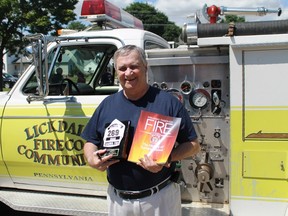 Author Phil Egan stands with a copy of his new book, Walking Through Fire: The History of Sarnia's Bravest, as well as a plaque given to him by Sarnia Fire Services during his book-singing event at East Street Fire Hall on July 15.
CARL HNATYSHYN/SARNIA THIS WEEK