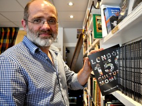 Jason Dickson, co-owner of Brown and Dickson Bookshop, pulls a copy of London: 150 Cultural Moments. Dickson co-authored the book, a funny and accessible cultural history of London, with partner Vanessa Brown. (CHRIS MONTANINI\LONDONER\POSTMEDIA NETWORK)