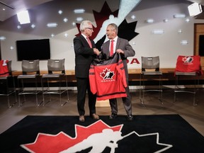 Hockey Canada's president and CEO Tom Renney, left, congratulates Team Canada's 2017-18 head coach Willie Desjardins at a news conference in Calgary on July 25, 2017. (THE CANADIAN PRESS/Jeff McIntosh)