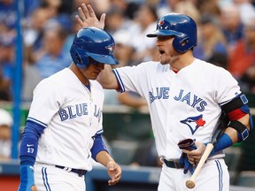 Toronto Blue Jays' Josh Donaldson, right, congratulates teammate Ryan Goins after scoring during MLB action in Toronto on July 25, 2017. (THE CANADIAN PRESS/Mark Blinch)
